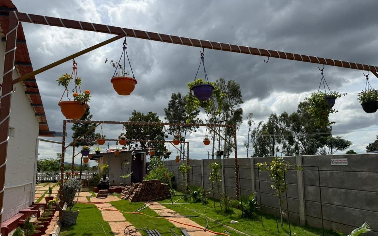 Garden seating area with hanging flower pots on rope-wrapped pergola frames
