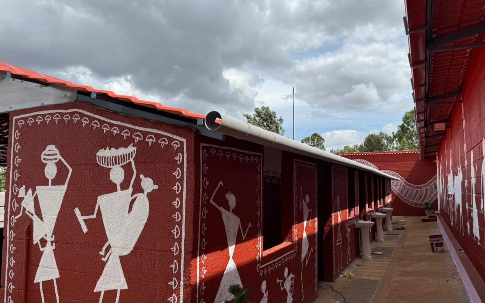 Warli tribal art painted in white on the deep-red outer wall